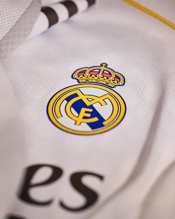 La camiseta incorpora unos ribetes amarillos, inspirados en el color del escudo, y cuenta con el cuello redondo.