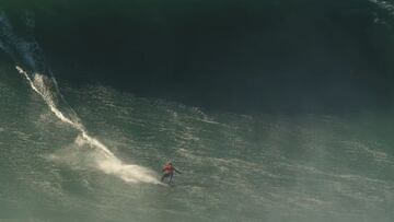 El surfista Lucas 'Chumbo' Chianca con una licra roja surfeando en el bottom de una ola gigante en Praia do Norte (Nazaré, Portugal) durante el swell XXL de diciembre. La sombra del labio está a punto de alcanzarle.