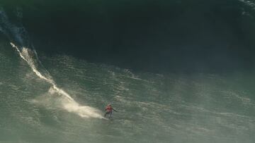 El surfista Lucas &#039;Chumbo&#039; Chianca con una licra roja surfeando en el bottom de una ola gigante en Praia do Norte (Nazar&eacute;, Portugal) durante el swell XXL de diciembre. La sombra del labio est&aacute; a punto de alcanzarle. 