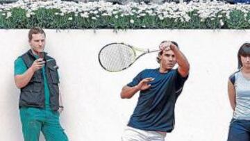 <b>PRIMERA FILA. </b>Uno de los operarios que pintaban a la vez los muretes de la pista fotografía a Nadal.