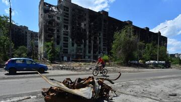 A man rides a bicycle past a destroyed apartment building in the city of Severodonetsk on July 12, 2022, amid the ongoing Russian military action in Ukraine. (Photo by Olga MALTSEVA / AFP) (Photo by OLGA MALTSEVA/AFP via Getty Images)