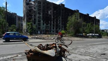 A man rides a bicycle past a destroyed apartment building in the city of Severodonetsk on July 12, 2022, amid the ongoing Russian military action in Ukraine. (Photo by Olga MALTSEVA / AFP) (Photo by OLGA MALTSEVA/AFP via Getty Images)