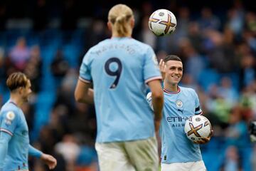 Phil Foden of Manchester City hands a match ball to team mate Erling Haaland