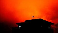 A house in Tajuya is seen with the Cumbre vieja volcano behind expelling lava and ash, on the Canary Island of La Palma, Spain, November 29, 2021. REUTERS/Borja Suarez