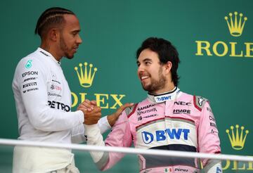 Lewis Hamilton y 'Checo' Pérez chocan la mano en lo alto del podio.