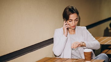 Woman talking on phone and drinking coffee outside in the street at night