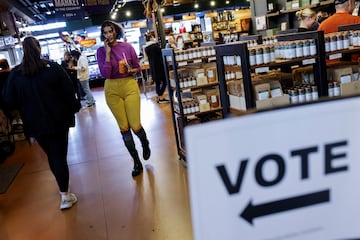 La gente camina junto a un cartel que indica dónde votar en las elecciones presidenciales estadounidenses, en Milwaukee, Wisconsin.