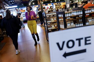 La gente camina junto a un cartel que indica dónde votar en las elecciones presidenciales estadounidenses, en Milwaukee, Wisconsin.