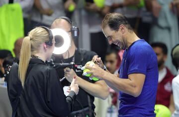 Rafa Nadal, entre risas, firma pelotas de tenis mientras un c¨¢mara graba la acci¨®n.