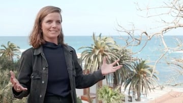 La surfista Lucy Small, vestida de calle, abre los brazos mientras habla de igualdad de género en un capítulo de una webserie de la World Surf League sobre el surf y las mujeres en Algeria. Con palmeras y el mar al fondo.