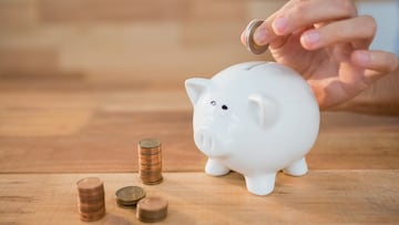Close-up of hand inserting coin in piggy bank