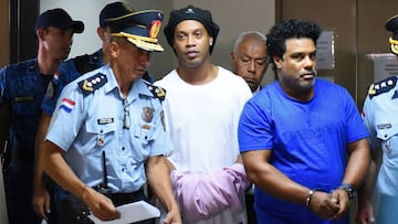 TOPSHOT - Brazilian retired football player Ronaldinho (C) and his brother Roberto Assis (R) arrive at Asuncion's Justice Palace to appear before a public prosecutor who will decide whether to grant them bail or not following their irregular entry to