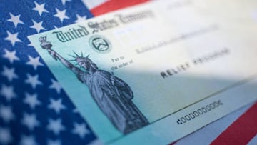 Cheque de est&iacute;mulo sobre la bandera de Estados Unidos v&iacute;a Getty Images.