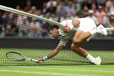Novak Djokovic cae sobre la red durante un duelo frente a Hubert Hurkacz en el partido de cuarta ronda de individuales masculinos del Campeonato de Wimbledon 2023.