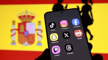 A Spanish flag and smartphone displaying social media app icons and children silhouette in this illustration taken February 3, 2026. REUTERS/Dado Ruvic/Illustration
