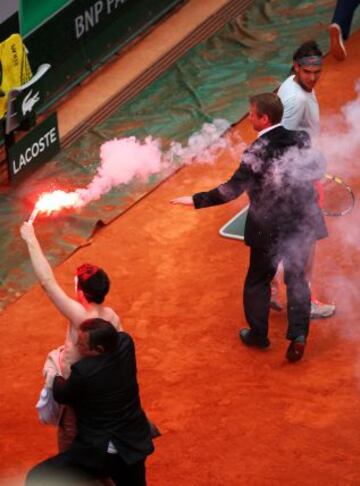 Un manifestante corre a la cancha con una bengala encendida durante el partido de la final individual masculina entre Rafael Nadal y David Ferrer en Roland Garros