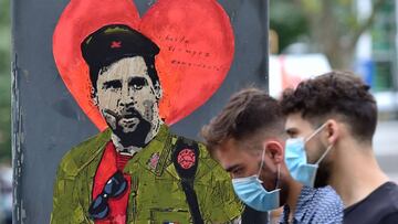 People walk past a new artwork by street artist TVBoy depicting Barcelona's Argentinian forward Lionel Messi entitled "Hasta Siempre Comandante" (Until Forever, Commander) in Barcelona on August 29, 2020. - Messi has provoked a football fre