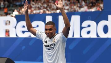 French forward Kylian Mbappe waves to the fans during a first appearance as a Real Madrid player at the Santiago Bernabeu Stadium in Madrid on July 16, 2024, after signing his new five-season contract. Still celebrating Spain's Euro 2024 triumph, Real Madrid fans have even more to cheer this July 16, 2024, as French superstar Kylian Mbappe is officially presented to a packed-out Santiago Bernabeu stadium. (Photo by Pierre-Philippe MARCOU / AFP)