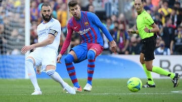 Real Madrid's French forward Karim Benzema (L) vies with Barcelona's Spanish defender Gerard Pique during the Spanish League football match between FC Barcelona and Real Madrid CF at the Camp Nou stadium in Barcelona on October 24, 2021. (Photo