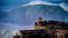 El surfista brasile&ntilde;o Vinicius Dos Santos (al fondo), surfeando una ola que podr&iacute;ai ser la m&aacute;s grande de la historia del surf, en Praia do Norte, Nazar&eacute; (Portugal) el 25 de febrero del 2022. En primer plano, mucha gente lo mira