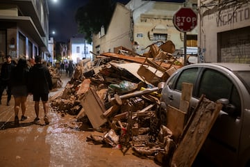 Varias personas caminan entre escombros en Benetusser, Valencia.