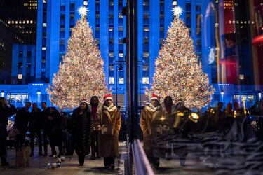 Una persona con un gorro de Papá Noel camina cerca del árbol de Navidad iluminado del Rockefeller Center durante la 93.ª ceremonia anual de encendido del árbol de Navidad del Rockefeller Center.
