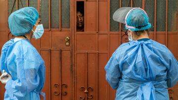 Health Ministry workers speak with a resident in the Ate district, on the eastern outskirts of Lima, on February 23, 2021, where residents are checked and have tests to discard COVID-19 done door to door. (Photo by ERNESTO BENAVIDES / AFP)