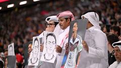 Aficionados cataríes, algunos con la boca tapada, sostienen fotos y dibujos de Mesut Özil.