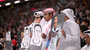 Aficionados catar¨ªes, algunos con la boca tapada, sostienen fotos y dibujos de Mesut ?zil.