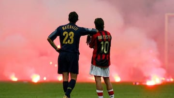 Inter Milan's Marco Materazzi (L) and AC Milan's Manuel Rui Costa waits on the pitch as supporters throw flares onto the pitch during their Champions League quarter-final second leg soccer match at the San Siro Stadium in Milan April 12, 2005.