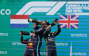 El piloto británico de Mercedes, ganador, Lewis Hamilton (C), el piloto holandés de Red Bull, Max Verstappen (L), y el piloto australiano de Renault, Daniel Ricciardo, tercero, beben champán en el podio después del Gran Premio de Eifel de Fórmula Uno de Alemania en el circuito de Nuerburgring