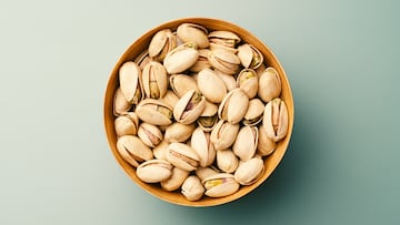 Pistachios in Wooden Bowl on Green Background Directly Above View.