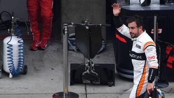 McLaren's Spanish driver Fernando Alonso (R) walks through the pit lane after retiring from the Formula One Chinese Grand Prix in Shanghai on April 9, 2017. / AFP PHOTO / Greg Baker