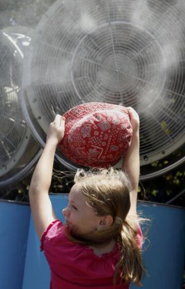 Una niña sostiene su sombrero mientras se refresca delante de un ventilador en el Abierto de 2014 de Australia en Melbourne