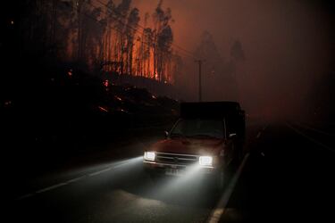 Un automóvil circula mientras el fuego y el humo se elevan de un incendio forestal en la región del Biobío, donde, según medios locales, múltiples incendios forestales provocaron evacuaciones de emergencia, en Concepción, Chile.