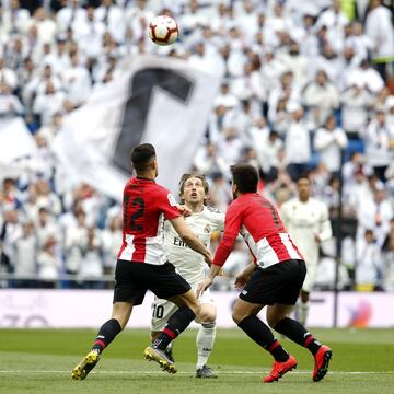 El jugador del Real Madrid Modric trata de controlar el balón ante los jugadores del Athletic Club Yuri y Beñat. 