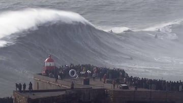 Ola gigante en Nazaré, 24 de febrero del 2024. Pico Big Mama, en Praia do Norte, con el faro de San Miguel Arcángel y mucho público en primer plano presenciando la ola surfeada por Lucas Chumbo Chianca.