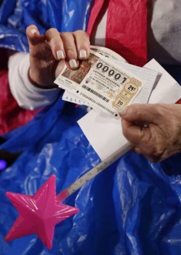 Una mujer sostiene un décimo de la Lotería de Navidad con el número 00001.