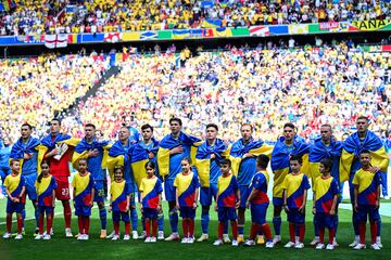 Los jugadores de Ucrania escuchan el himno de su país envueltos en su bandera.