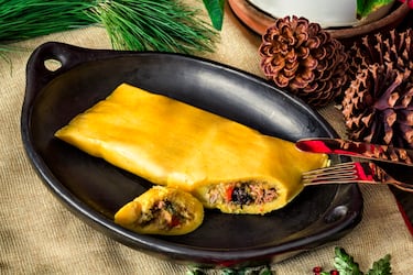 Venezuelan traditional Christmas food: Hallacas on rustic dish.

Considerada el plato nacional navideño. Es un tamal envuelto en hojas de plátano, relleno de un guiso de carne de res, cerdo y/o pollo, con verduras, pasas, aceitunas y alcaparras. La preparación es un ritual familiar.