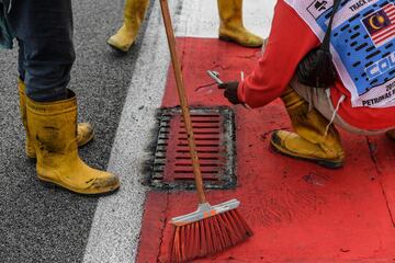 Los operarios del circuito de Sepang arreglan la alcantarilla que provocó el accidente del piloto francés.