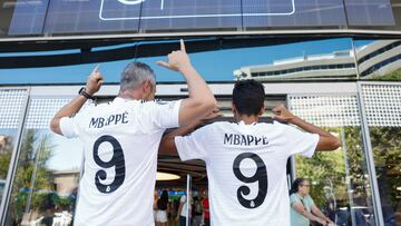 Dos aficionados madridistas posan enfrente de la tienda del estadio Santiago Bernabéu con sendas camisetas de Mbappé.