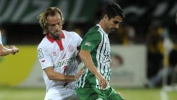 El jugador de Atl&eacute;tico Nacional, Juan Pablo Angel, disputa el bal&oacute;n con Ivan Rakitic del Sevilla.