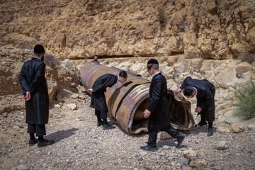 Judíos ultraortodoxos observan parte de un misil balístico interceptado que cayó en el desierto cerca de la ciudad de Arad, Israel, el 28 de abril.