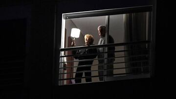 A couple follows the "show" as Argentine DJ Juan Martinez plays loud music from his balcony animating his neighbourhood as every Friday since President Alberto Fernandez ordered a general lockdown to curb the spread of the new coronavirus, COVID-19, in Colegiales neighbourhood in Buenos Aires, on April 10 2020. - In a message to the nation earlier, the Argentine president extended the "preventative and compulsory" lockdown until April 26. (Photo by Ronaldo SCHEMIDT / AFP)