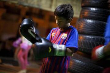 Un niño se pone guantes de boxeo antes de una lección de Muay Thai en el Alto Perú barrio de chabolas de Lima.  Desde 2008, la ONG Alto Perú busca ofrecer a los niños de un barrio pobre de pescadores conocido como Alto Perú, la oportunidad de aprender y practicar deportes alternativos como el surf y el Muay Thai de forma gratuita.