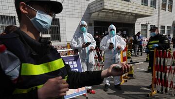 Workers in protective suits check registration codes as people enter a nucleic acid testing site, following the coronavirus disease (COVID-19) outbreak, in Beijing, China April 6, 2022. REUTERS/Tingshu Wang