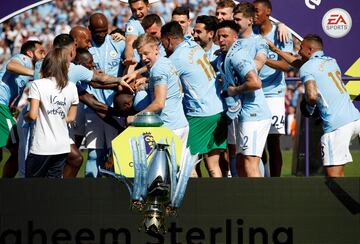 El trofeo de campeón de la Premier League se cae mientras los jugadores del Manchester City celebran el título. 