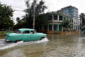 Un automóvil clásico cruza una calle inundada mientras el huracán Milton pasa cerca de la costa cubana en La Habana, Cuba.