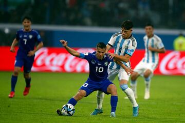 Uzbekistan's Umarali Rahmonaliyev holds off Argentina defender Agustin Giay.